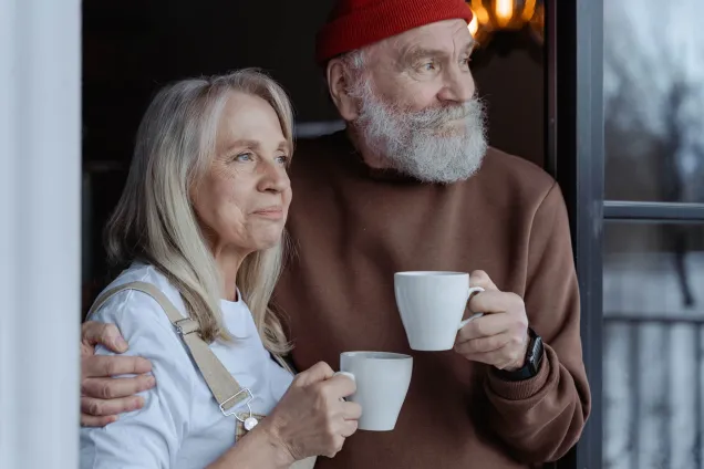 couple looking outside holding cups 